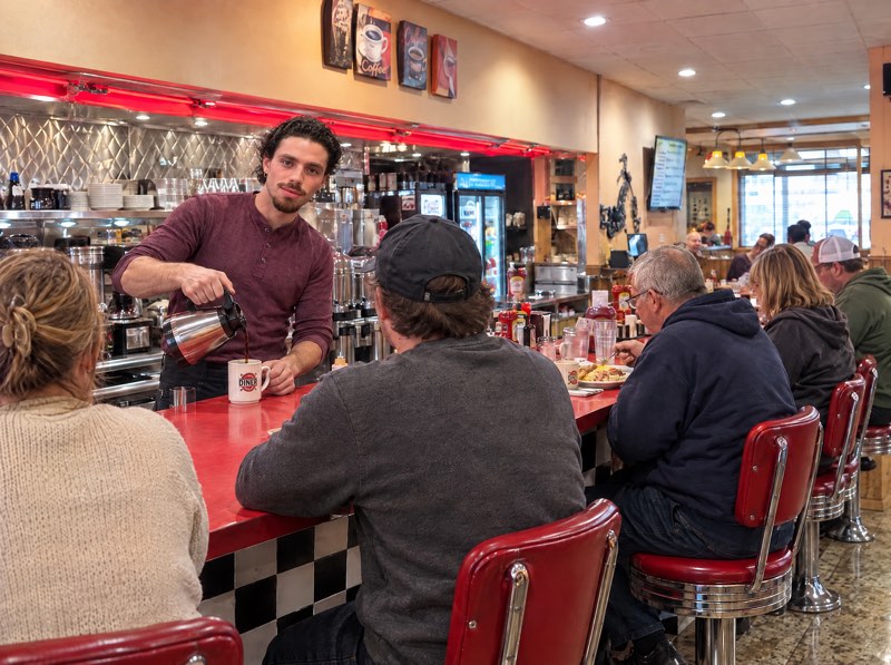Hesam pouring coffee for guests at the Highway Cafe counter